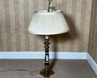 GREEK-STYLE TABLE LAMP | Brass tripod base supporting a black column with white raised laurel leaves and the figure of a woman holding a bird, having two light bulbs and chain pulls, with adjustable pleated shade and feather-form handle / finial; overall h. 26 in.