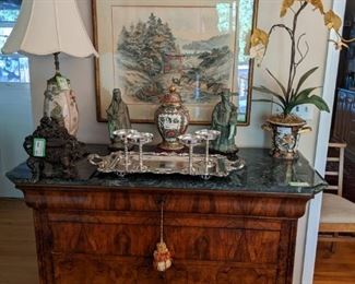 Antique 5-drawer French chest, w/green marble top, pair of Asian bronze figurines on custom wooden bases, bronze Asian censer, porcelain Asian table lamp, Asian porcelain ginger jar on wooden base, nicely framed/matted vintage Asian artwork, faux orchid in Imari vase, Sheffield silverplated/footed serving tray, set/w silverplated champaign coupes and hand-carved wooden dragon, feeling above it all.