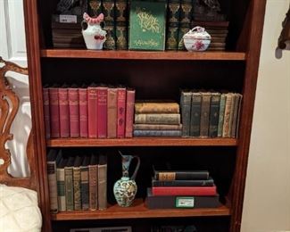 Wooden bookshelf with vintage book collection and assorted doo dads.