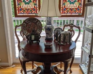 Very functional and unexpected trick that this unassuming 1940's mahogany drum table can do - it has three leaves and drop-down legs that convert to a dining table, when needed. There's also a vintage bronze Asian censer, blue/white porcelain table lamp, w/shade/finial, 4-section Asian porcelain lunchbox, set/4 carved soapstone Asian figurines, all happily lorded over by a handsome pair of stained glass windows, in wooden frames.
