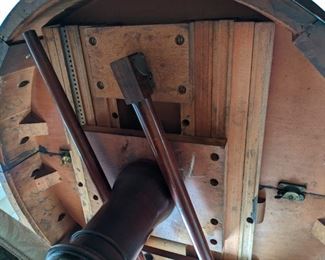 This is the underside of the 1940's mahogany drum table, showing the drop-down legs and sliding mechanism that allow the drum table to convert to a dining table in a flash.