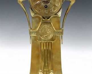 A turn of century Lenzkirch Art Nouveau Brass table clock.  14-day time only movement with platform escapement, cast Brass dial and Arabic numerals, serial # 1 Million 435628.   Cast Brass case with rounded top, shaped arms, "Father Time" detail in relief, floral drops and a molded base.  Polished case with minor wear, running momentarily when cataloged.  14 1/2" high.  ESTIMATE $600-800