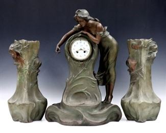 A late 19th century French Art Nouveau Period 3 pc clock set by Samuel Marti, Paris.  8-day time and strike movement with hand painted porcelain dial and Arabic numerals, serial #84692.  Figural Spelter case and matching vases marked "A De Ranieri" and "Horan" respectively, clock depicts a woman standing beside a fountain and the vases have women and cherubs.  Original Green/Brown patina with some wear, running when cataloged.  22 3/4" and 17" high.   ESTIMATE $800-1,200