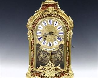 A late 19th century French Boulle Louis XV style mantle clock with base by Japy Freres.  8-day time and strike movement with cast Bronze dial and porcelain markers with Roman numerals and engraved minutes above the retailer's marquee "Bataille A Paris"  with Apollo Mask pendulum, stamped maker's mark.   Red Boulle case with Brass Marquetry inlay and gilded Bronze mounts including a figural finial, foliate scrolls, lower door medallion and scrolled feet.  Minor wear, some older repairs, hairline in Marquee, repaired split in base, running when cataloged.  21 1/2" high.  EATIMATE $1,500-2,500