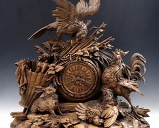An Exceptional 19th century Black Forest carved Walnut table clock with on-demand music box.  8-day  Brass time and strike movement with carved wooden dial and Brass Roman numerals, serial #117699, with an on-demand cylinder music box having pull string winding and play, marked "J L C" on plate.  Exceptional hand carved Walnut case features a Hawk sitting on a farmer's harvest basket looking down at a rabbit, rooster, hen and two chicks with Wheat sheaves, logs, rock and foliate detail.  Old finish with slight wear and minor damage, running and functioning when cataloged.  33 1/2 x 13 x 34" high overall.  ESTIMATE $6,000-8,000