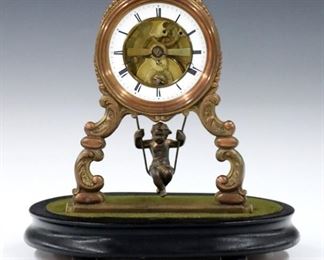 A late 19th century French "Cherub on a Swing" mantle clock by Eugene Farcot.  8-day time only skeletonized movement with porcelain chapter ring and Roman numerals has a Farcot patent swinger escapement with double escape wheel, and cast pendulum with Cherub, movement signed, "Chappement Brevete" with Eagle Trademark, serial #60261.  Scrolled Brass supports with Copper and Gilded finish on a Black wooden base with glass dome.  Some wear, dome replaced, running when cataloged.  9 3/4" high.  ESTIMATE $400-600