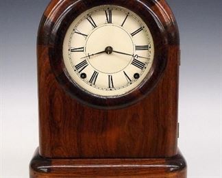 A late 19th century Seth Thomas, Plymouth Hollow round top shelf clock.  8-day Lyre shaped time and strike movement with painted metal dial, Roman numerals and "S T" hands.  Rosewood case with round molded top over a single long door with clear dial glass on a simple molded base.  Paper label 80% intact.  Refinished with minor wear, tiny veneer flake on door, running when cataloged.  15" high.  ESTIMATE $200-300