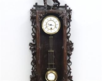 A 19th century Dwarf Vienna Regulator wall clock.  8-day spring driven time only movement with a 3 1/2" two-part porcelain dial, Roman numerals and molded Brass bezel and gridiron "R A" pendulum.  Black Forest carved Walnut case with a carved Mountain Goat crest, case with pierced foliate carvings and lower Dog's head.  Old finish with minor wear, dial hairlines,  running when cataloged.  25 1/2" high overall.  ESTIMATE $400-600
