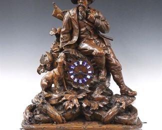 A 19th century Leuenberger Black Forest carved Walnut table clock with lower multi-tune music box.  8-day Brass time and strike movement with carved wooden dial and Blue porcelain Roman numeral markers, marked "Leuenberger, Interlaken" serial #1649, with lower hour/on-demand cylinder music box with independent key wind at base.  Exceptional hand carved Walnut case features a Hunter seated with his Schuetzen rifle on his back and hunting dog at his feet with  tree root and foliate detail.  Old finish with slight wear and minor damage, replaced hands, touch ups to 12 o'clock marker, running and functioning when cataloged.  22 x 12 x 26" high overall.  ESTIMATE $4,000-6,000
