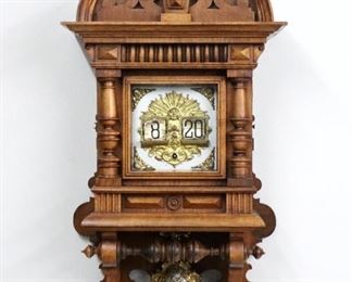 A late 19th century Lenzkirch Digital Freischwinger wall clock.  The digital or "flip" clock was conceived by the Austrian inventor and engineer Josef Pallweber in 1890 and produced  by the world-renowned Lenzkirch Clock Factory between 1893-1894.  This clock features an 8-day time only movement with Silvered dial and gilded Bronze Apollo mask decoration and original cast two-tone pendulum, serial # 1 Million 2879 (1893).   Walnut case with shaped crown and carved shell finial, single door with square glass and turned pilasters over a shaped drop with turned rail and applied bosses.  Older finish with  minor wear, some dial discoloration, running when cataloged.  35 1/2" high overall.  ESTIMATE 2,000-3,000
