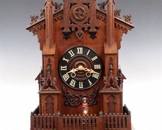 An early 20th century German Black Forest mantle cuckoo shelf clock with "Marching Sentry" automaton.  Brass 8-day time and strike movement with "L B" trademark, Cuckoo and Gong strike, wooden dial with applied Roman numerals.  Oak Gothic Revival case with spires on tall columns and a pediment crest over a carved wooden fence with painted Sentry figure, over a stepped molded base with carved frieze.  Original finish with Ebonized detail, small repairs, running and functioning when cataloged. 27 1/4" high. ESTIMATE $3,000-4,000