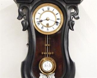 A 20th century Miniature Vienna Regulator wall clock.  8-day spring driven time only movement with silk thread suspension and a 3 1/4" flat porcelain dial, Roman numerals and molded Brass bezel.  Mahogany Serpentine case with a carved crest and shaped molded crown over a single shaped door and shaped drop with turned finial.  Refinished with some wear, dial wear, restored crest and lower finial, running when cataloged.  22 1/4" high overall.  ESTIMATE $600-800