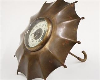 A turn of the century Umbrella form novelty clock.  30 hour time and alarm movement with porcelain chapter ring, Arabic numerals and embossed dial center.  Brass umbrella case, handle removes for winding.  Some surface wear, running when cataloged.  5 1/2" high.  ESTIMATE $100-150