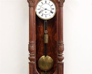 A 19th century Lenzkirch Vienna Regulator wall clock.  30-day weight driven time only movement with two-part porcelain dial, Roman numerals and molded Brass bezel, serial #33353.  Walnut case with hand carved decoration features an arched crest with foliate frieze above an arched door with carved fluted pilasters and a shaped molded drop with carved finials.  Older refinishing with restoration, small dial flakes at winding arbor, running when cataloged.   49 1/2" high overall.  ESTIMATE $1,000-2,000