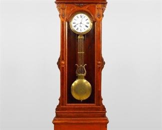 A late 19th century New Haven No. 4 model floor standing Jewelers Regulator.  8-day wright driven French movement with pinwheel escapement, sweep seconds, porcelain dial with Roman numerals and bi-metallic gridiron pendulum with lyre.  Three section American Victorian Renaissance Revival Black Walnut case with Burl panels and carved detail features an arched crest with carved fan and applied medallion with lower swag over a paneled frieze and long door with carved "ears" and a paneled base with a molded plinth.  Older refinishing with minor wear, chip in one iron movement bracket, pendulum pitting, running when cataloged.  126" high overall.  ESTIMATE $4,000-6,000