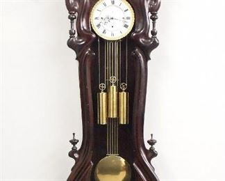 A 19th century Vienna Regulator wall clock.  30-day weight driven movement with quarter hour Grand Sonnerie strike and a two-part porcelain dial with Roman numerals, a Bronze piecrust bezel, and bi-metallic compensating pendulum.  Mahogany Serpentine case features a molded arched crown with shaped block and finials over a single shaped door with filigree detail and turned finials, shaped lower drop with turned finials.  Refinished with restorations, some replaced finials, running when cataloged.  69 1/2" high overall.  ESTIMATE $3,000-5,000