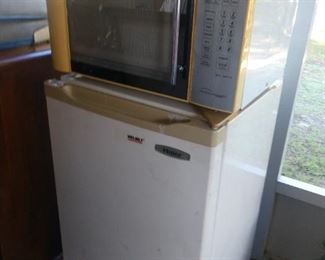 Microwave sitting on top of small Frig.