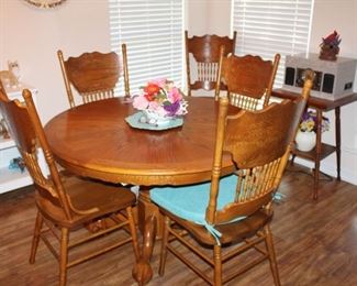48" round solid-wood table, plus a 24" leaf; six pressed-back chairs