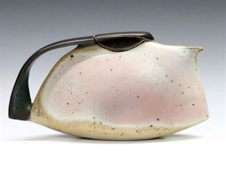 A late 20th century Stoneware teapot by Gerald and Gotlind Weigel. Flat stylized form with matte glaze in subtle tones of Slate Gray, Mauve and Blue. Stamped studio mark at side by handle, incised "Weigel" signature and dated "99" at base. Minor wear. 10 1/2 x 2 1/2 x 5 1/2" high overall. ESTIMATE $300-400