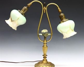 An early 20th century American desk lamp with Quezal Art Glass shades. Patinated Bronze base with cast polychrome flower flanked by adjustable gooseneck arms and iridescent Green pulled feather shades. Shades signed "Quezal" at fitter. Some wear to patina, one switch needs replacing, cast flower slightly loose. 18" high. ESTIMATE $400-600