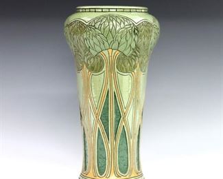 An early 20th century Roseville Rozane "Della Robbia" line Art Pottery vase designed by Frederick Hurten Rhead.  Shape #58, having a flared form and rounded shoulders, with multi-color glaze and incised decoration depicting Arts and Craft style trees.  "N.E." artist initials at foot, partial "Rozane Ware" seal at base.  Drilled for use as lamp, some crazing and chips to glaze up to 1/4" long.  10 1/2" high.  ESTIMATE $2,000-3,000