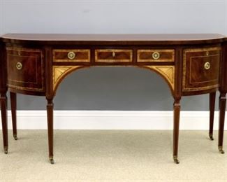 A Baker Hepplewhite style sideboard. Mahogany construction with contrasting Satinwood banding, inlaid fans and contrasting stringing. Features a shaped top over three short dovetailed drawers flanked by shaped doors on tall tapered legs with Brass castors. Original finish with slight wear and minor surface dings. 72 1/2 x 25 1/4 x 37" high. ESTIMATE $1,000-1,500
