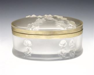 A late 20th century Lalique "Coppelia" pattern Crystal vanity box. Oval form with Gilt metal rims and frosted rose branch decoration in hollow relief. Etched "Lalique France" signature. Minor wear, one scratch to base. 7 x 5 1/2 x 3 1/4" high overall. ESTIMATE $200-300