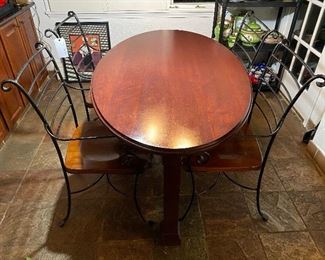 Small oval kitchen table. Chairs are heavy wrought iron frame with a solid wood seat