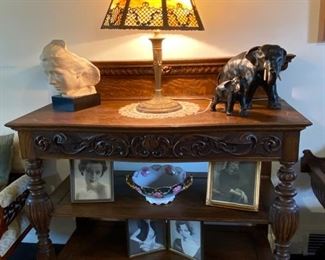 Carved Jacobean-style oak buffet, c1800s. Art Deco brown slag glass table lamp. Bust of silent movie actress, Maude Adams. Cast iron elephants.