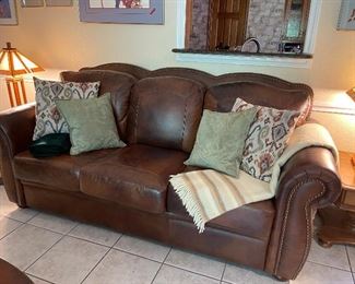 Leather sofa with nail head detail, cushions. 