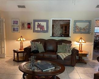 Looking at the leather sofa, and Amado M Pena print collection. Two beautiful Arts and Craft style stained glass table lamps, vintage side tables