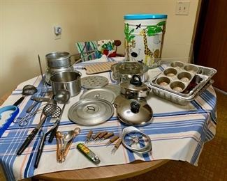 Kitchenware: double-boiler, muffin tins, assorted pans and lids, measuring spoons, strainers, masher, ladle, apple corer, vintage aprons