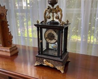 French Mantel Clock: portico column, four glass panel case, ormolu gold gilt feet, lion embellishment, hand painted porcelain pendulum, rose vein marble base, key wind