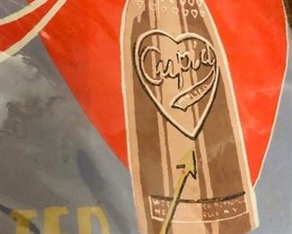 Behold, an original paperboard Cupid Chocloate Malted Dairy Drink Sign going up for your consideration on Tuesday evening with a reasonable reserve. 

You may have seen a similar version as this sign was reworked and reproduced in tin as a decor item in modern times on account of its amazing graphics but nothing compares to how breathtaking the original is. 

This sign is often incorrectly attributed to the 1930s. It is more likely to have been created in 1909-1910 on account of the construction of the sign, the typeface and print style and the fact the Westchester Bottling Wks of New Rochelle, NY was in bankruptcy by 1911 on account of overextending themselves with expansion plans the years previous. 

If you’re a Victorian era paper collector, a beverage sign collector, an antique Valentine enthusiast or into quackery, this is an excellent piece to add to your collection. Measures 22”x14.25” - some stippling bottom left and worn to rounded corners from age. It’s currently plastic wra