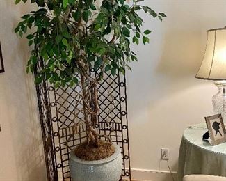 Large faux plant in a large celadon pot and wooden base.