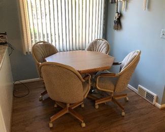 Retro kitchen table or game table with 4 upholstered chairs on casters. Oak accents. Formica tabletop.