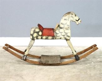 A turn of the century child's rocking horse.  Carved wooden horse with original dappled paint and curved rockers.  Significant wear to paint, damage to saddle.  11 x 45 x 24" high overall.  ESTIMATE $200-300