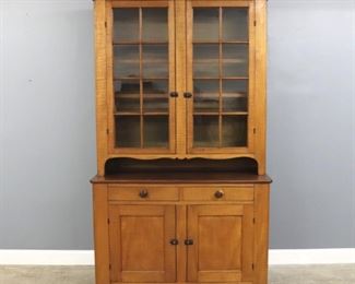A 19th century Ohio Step Back cupboard.  Curly Maple construction with a Walnut crown and work surface, upper section has two 8 pane doors with Iron latches, over a shaped pie shelf on a base with two dovetailed drawers, two paneled doors and simple cutout feet.  Old finish with minor wear.  15 1/2 x 20 1/2 x 90" high overall.  ESTIMATE $1,000-2,000