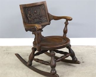 A late 19th century American rocking chair.  Oak construction with carved tavern scene in back, scrolled arms with turned supports, circular seat with turned design on a heavy turned stretcher base with shaped rockers.  Original finish with wear, joint separation to seat.  20 1/2 x 30 x 31 1/2" high overall.  ESTIMATE $100-150
