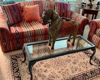 Couch and Love Seat, large wooden antique horse, rug, and glass/iron and wood coffee table.