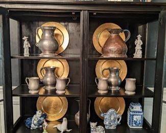 Contemporary lighted china cabinet, with two bottom storage drawers. The top is filled with a pair of Asian porcelain figurines, pair of white glazed foo dogs and blue/white porcelain ginger jar.                                                 The interior is filled with a collection of French pewter, by Les Etains, a vintage copper/tin pitcher, blue/white Asian porcelain lidded jar, dragon teapot, 2-piece cat dish, and demented man carefully cradling his favorite pet koi. 