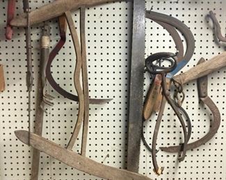 Assorted hand tools including saws, scythes, machetes and more