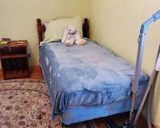 Single twin bed. 
Green oval rug.
Electrolux vacuum. 