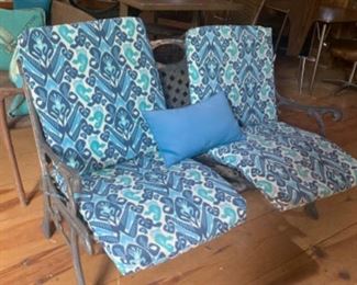 A wood and cast iron bench is under the cushions.