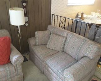 Small Matching 2 Seater Fabric Couch. Brass Tall Lamp. Weather Barometer on Wall.