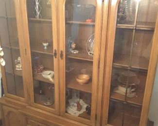 Tall Glass and Wood Breakfront Cabinet in Living Room. Decorative Travel Souvenirs displayed.