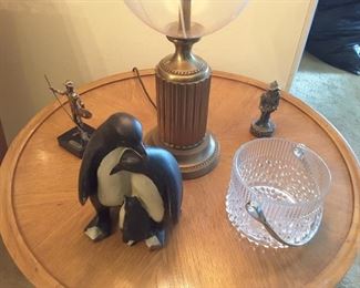 Round Oak End Table with decorations: Hugging Penguins, Glass Ice Bucket, Don Quixote Bronze Figure, Spaniard Figure. Bronze Glass Lamp.