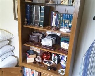 Tall Book Shelf, 4 Shelves. 2 Lower Shelves with Doors. Various Rick Steve's Travel Book Collection and Travel Toiletry Bags and Collectibles.