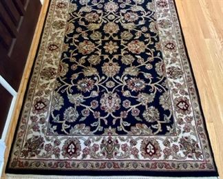 Oriental Rug at the entryway, black, tan, cream, burgundy with fringe trim.