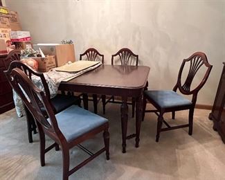 Mahogany dining room table, 5 armless chairs, one Captain’s chair, pads, 2 leaves